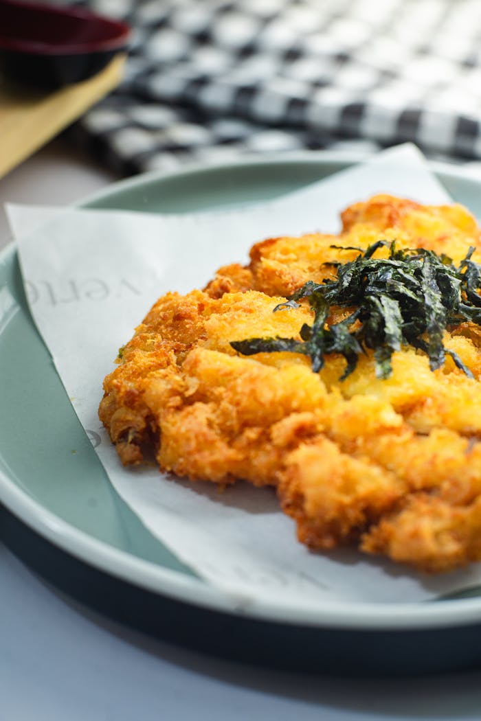 Delicious crispy chicken katsu garnished with seaweed, perfectly plated for a creative food presentation.